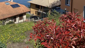 A building with a tiled roof and a balcony overlooking a lake with mountains in the background.