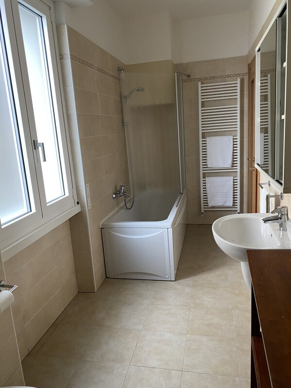 A bathroom with a bathtub, a sink, and a shower. - Sosta Sul Lago (Lezzeno)
