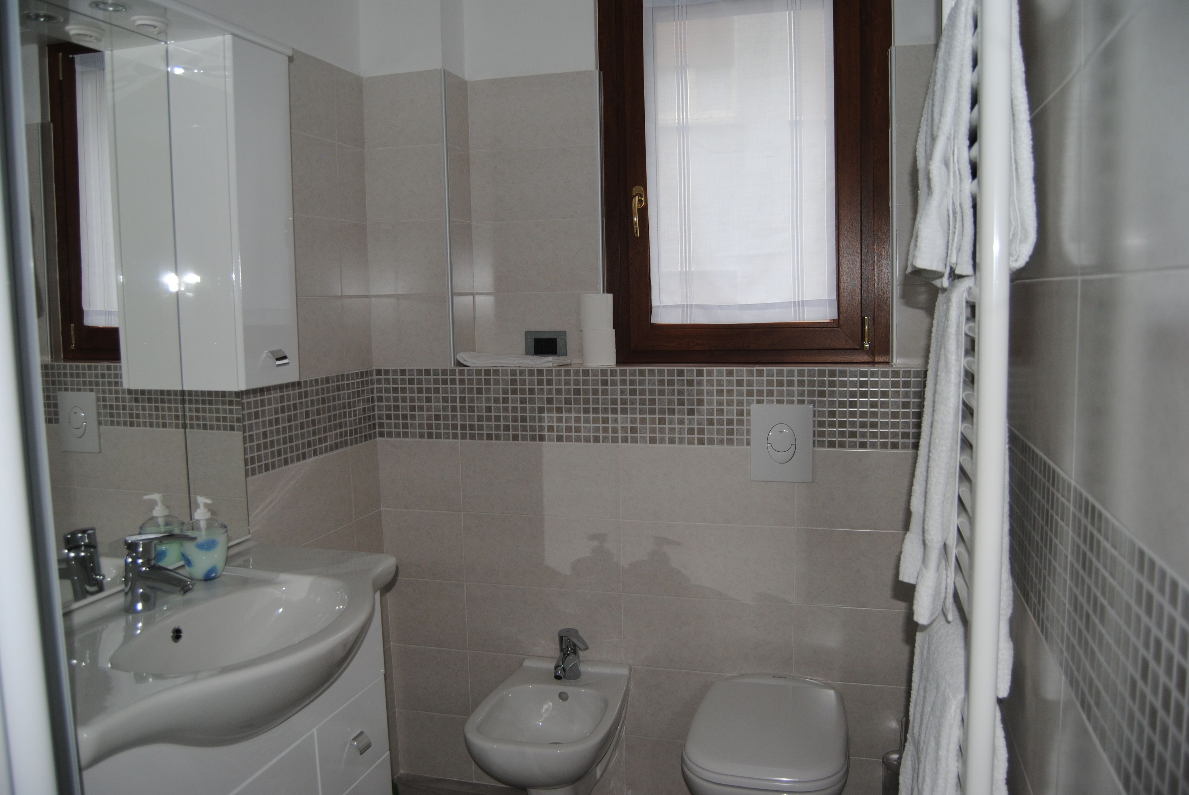 A bathroom with a sink, bidet, toilet, and a mirror.