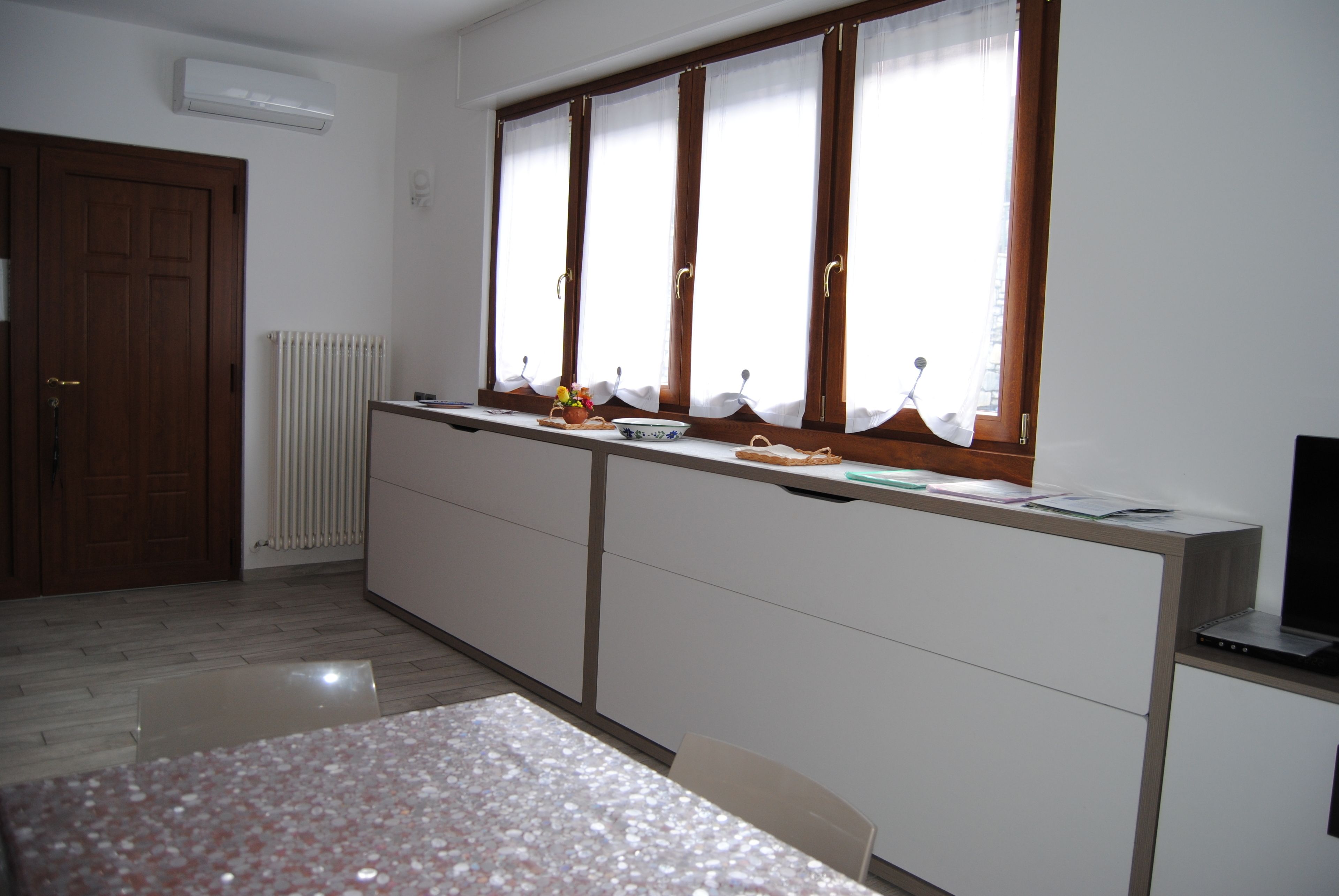 Een keuken met een raam, een radiator, een deur en een tafel.