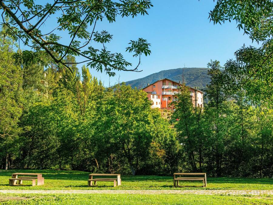 Um parque com bancos e um edifício ao fundo.