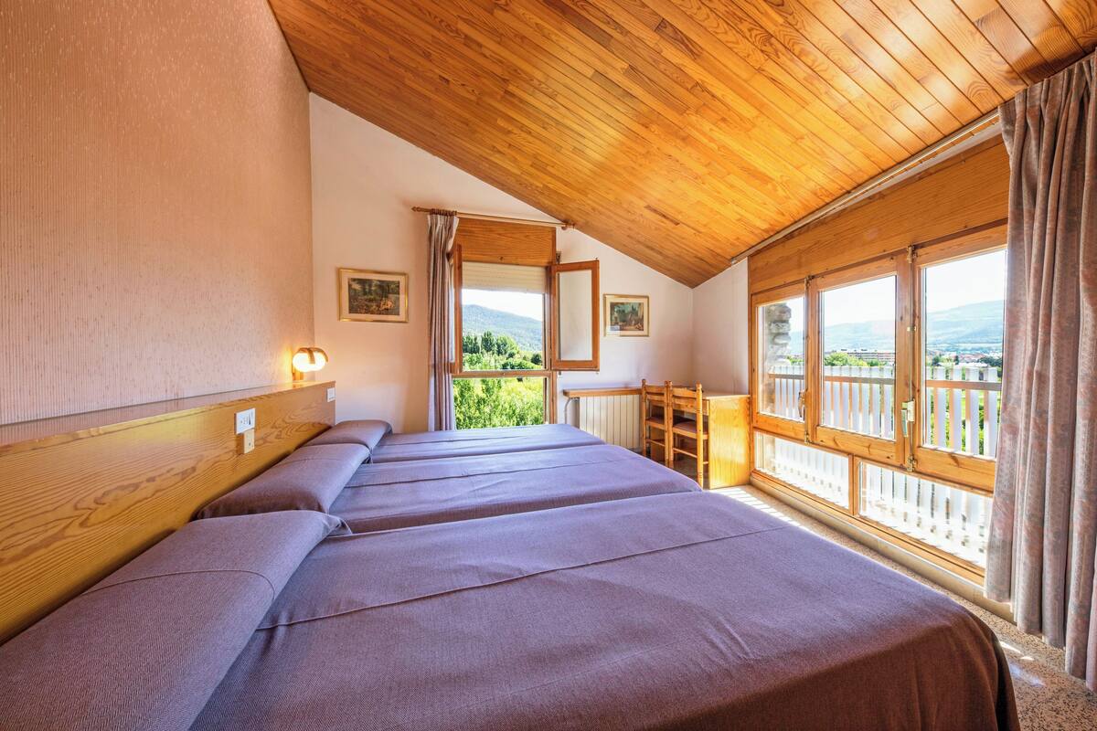 Un dormitorio con techo de madera, ventanas amplias y vistas al exterior.
