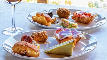 Two plates of assorted pastries and a glass of wine on a table.