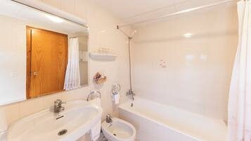 A bathroom with two sinks, a bidet, and a bathtub.