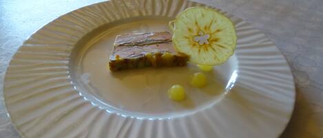 A plate with a slice of meat, a slice of apple, and some corn kernels.