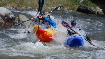 Tres kayakistas remando por un río con rápidos.