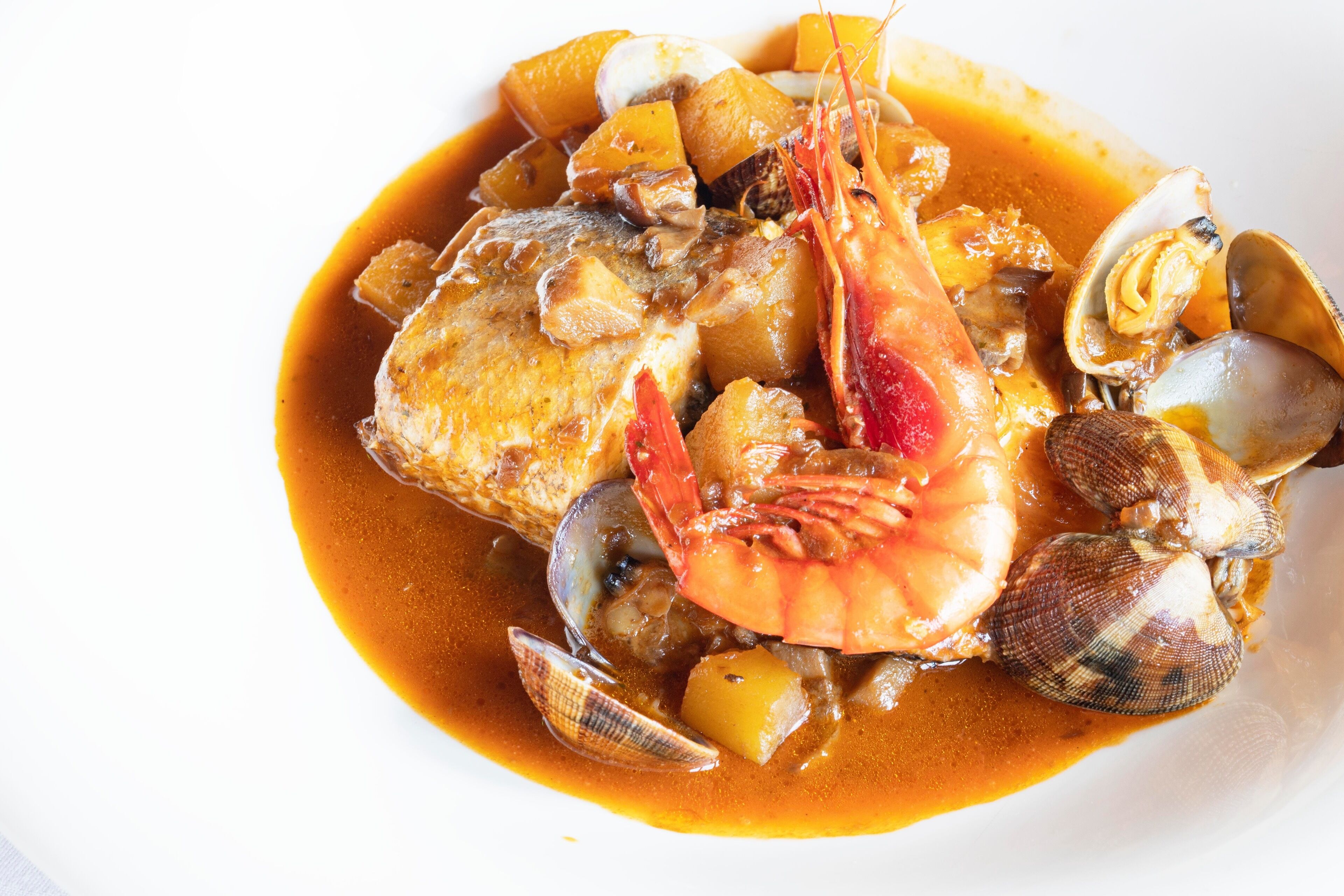 Plat de marisc amb cloïsses i gambes sobre un plat blanc.