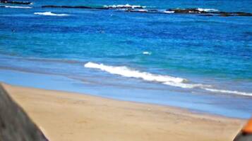 A beach with clear blue water and a sandy shore.