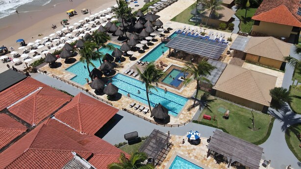 A resort with multiple swimming pools, beach access, and palm trees.