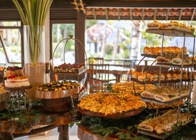Un bufé con diversos alimentos expuestos en puestos escalonados y un pastel sobre un soporte de madera.