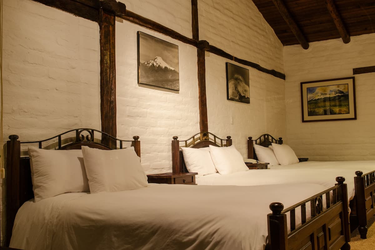 A room with two wooden beds, white bedding, and wooden headboards.