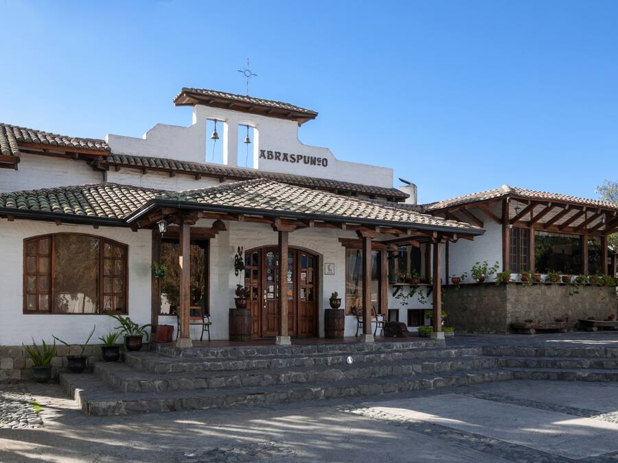 A traditional building with a tiled roof, a sign reading "ABRASPUNO," and a stone staircase leading to the entrance.