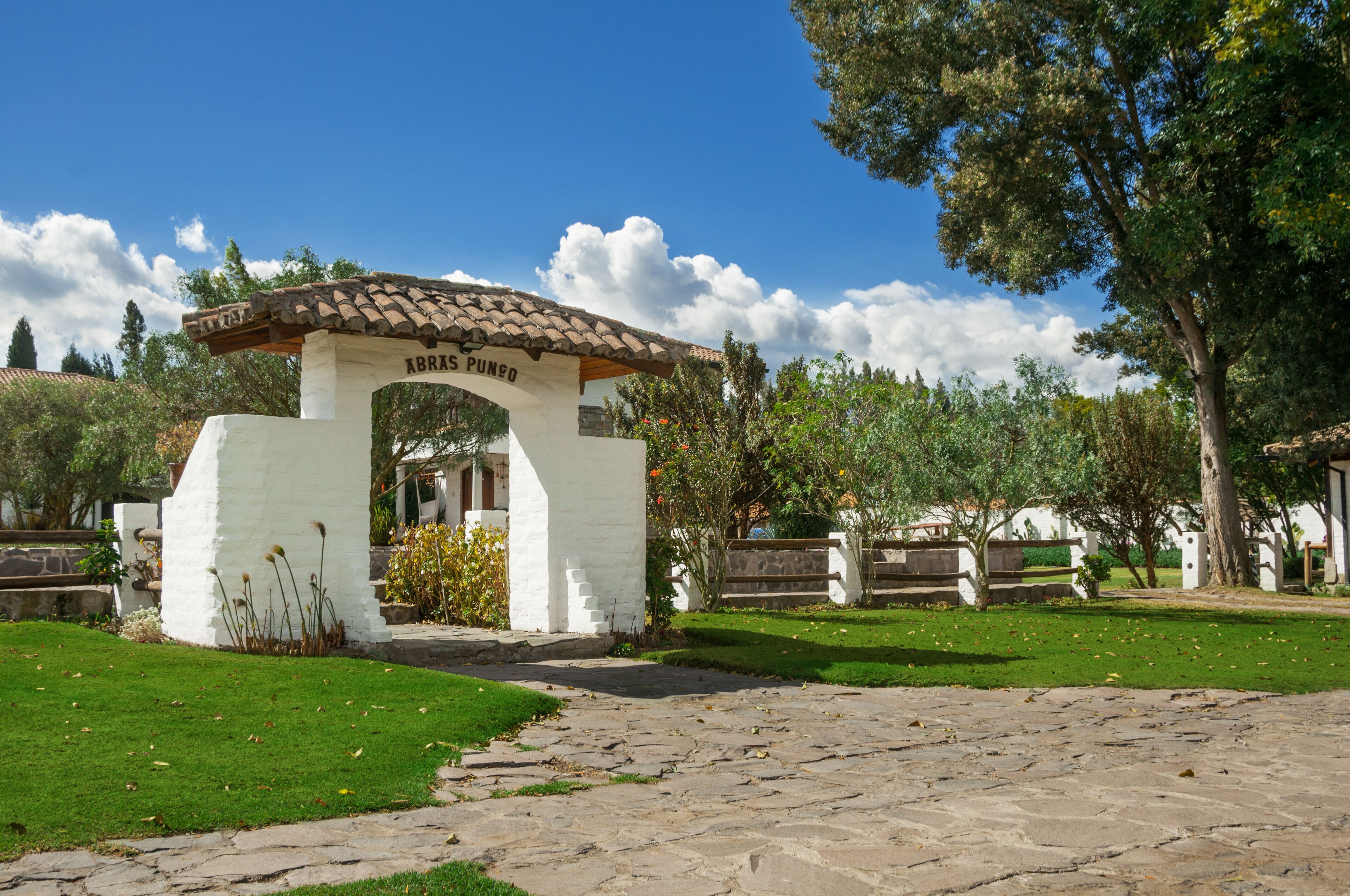 A white building with a tiled roof and the inscription "ABRAS POMED" on its entrance.