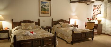 Habitación de hotel con dos camas de madera, un cuadro en la pared y un tapiz decorativo.