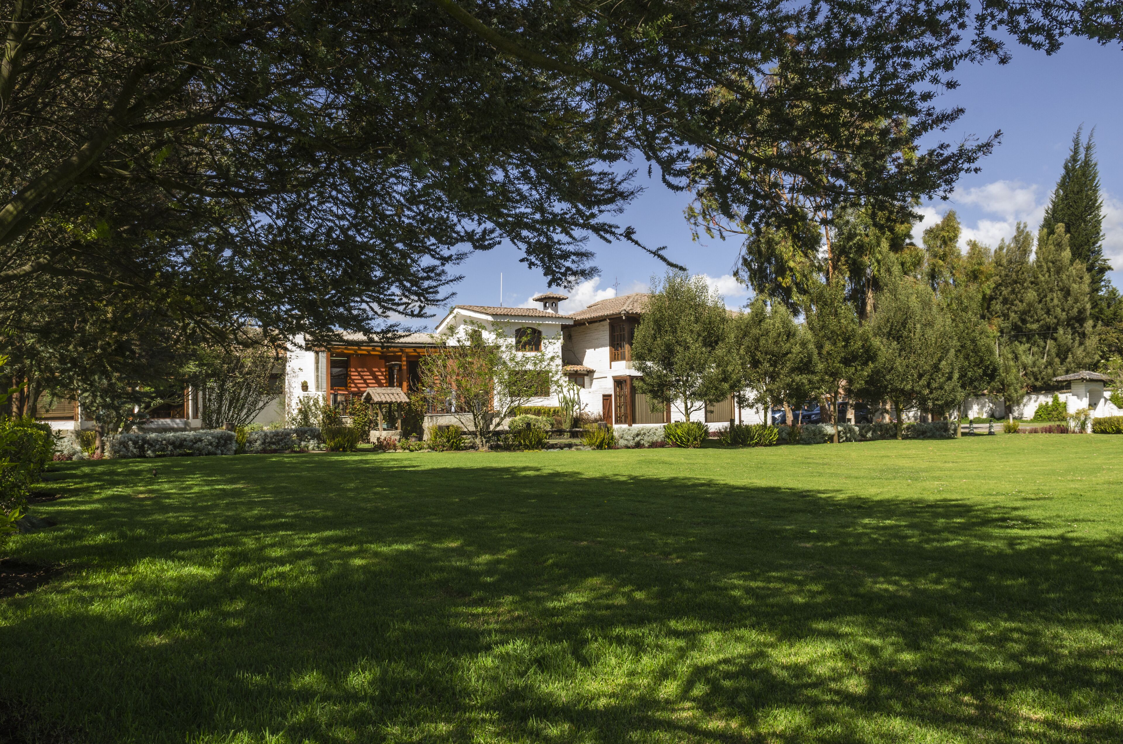 A residential property with a large lawn, a wooden deck, and a white building with a tiled roof.