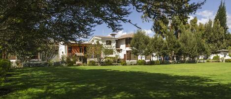 A residential property with a large lawn, a wooden deck, and a white building with a tiled roof.