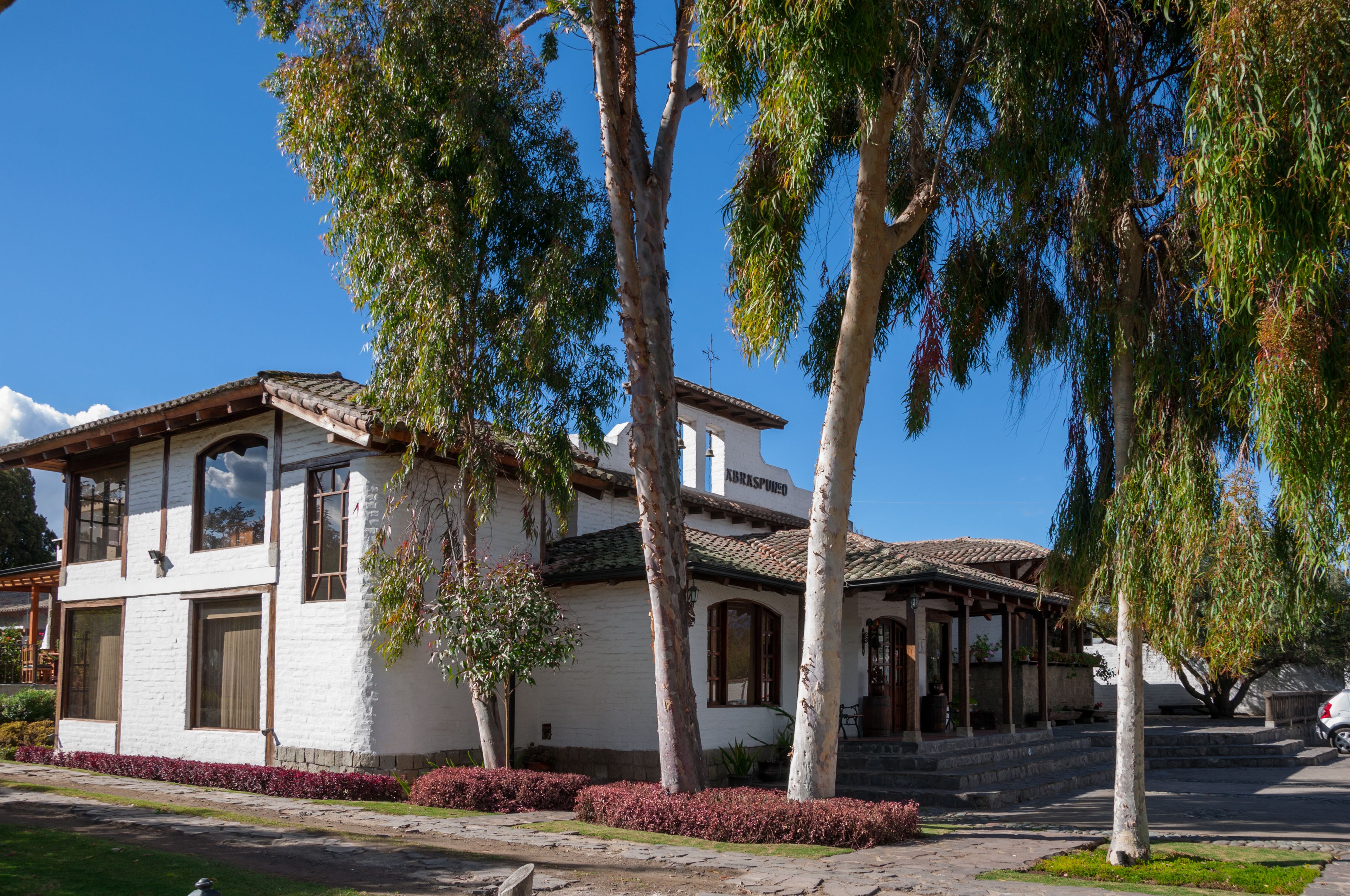 A two-story house with a white facade, large windows, and a tiled roof.