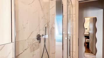 Une salle de bain moderne avec une douche à parois de verre, des carreaux de marbre et un plancher en bois.