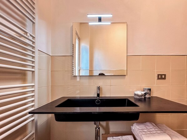 A bathroom with a black sink, a mirror, and a towel rack. - Hotel Alba (Lavagna)