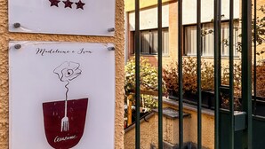 Two signs on a building: one for a hotel named "Hotel Alba" with three stars, and another for a restaurant named "Madeline e Iva" with a wine glass logo. - Hotel Alba (Lavagna)