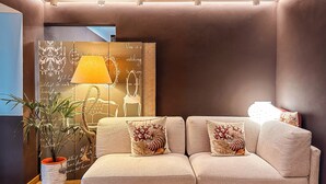 A modern living room with a beige sofa, decorative pillows, a potted plant, and a wall art piece. - Hotel Alba (Lavagna)