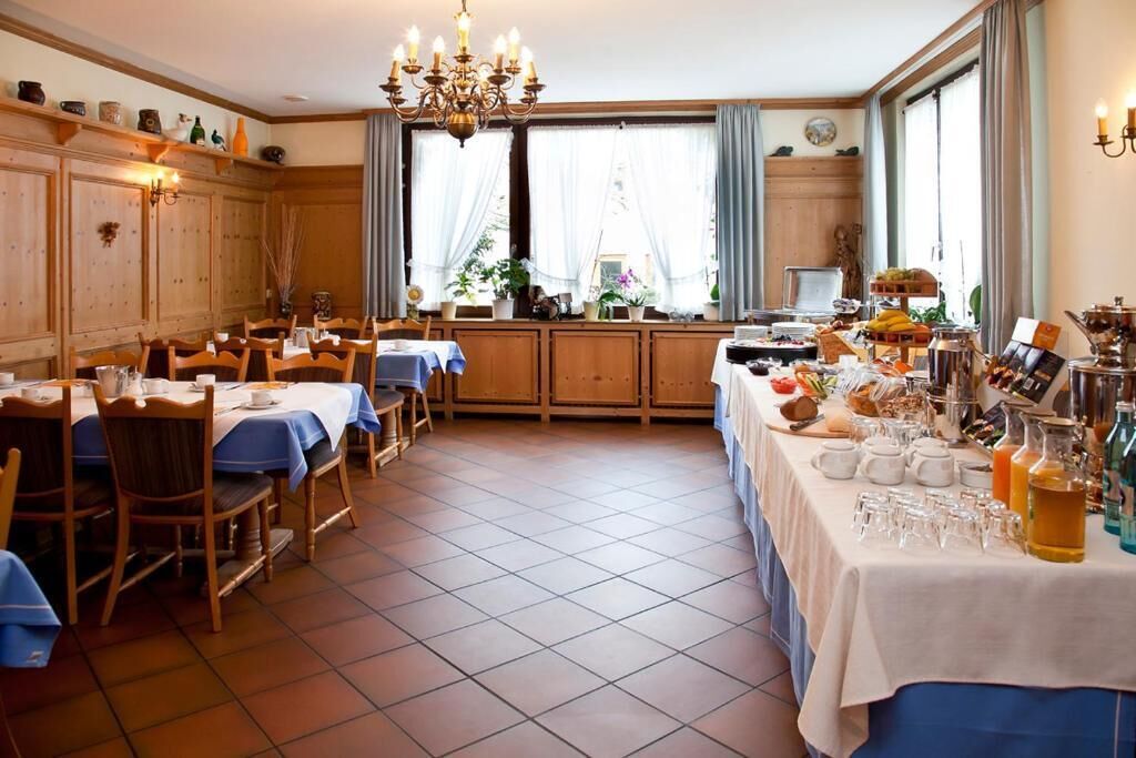 Een eetruimte met meerdere tafels, stoelen en een buffet.