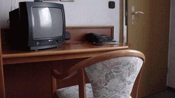 Una habitación con un escritorio de madera, un televisor y un teléfono.
