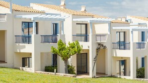 A modern multi-story residential building with balconies, a tiled roof, and a small tree in the foreground. -  Bimbolla Apartaments (Sant Lluis)
