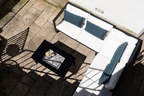 Un patio con un sofá blanco y una mesa de centro negra.