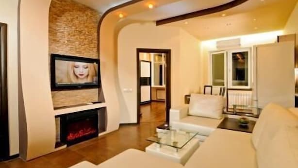 A modern living room with a fireplace, a flat-screen TV mounted on a stone wall, and a sofa with a glass coffee table. - Lukyanovsky (Kyiv)