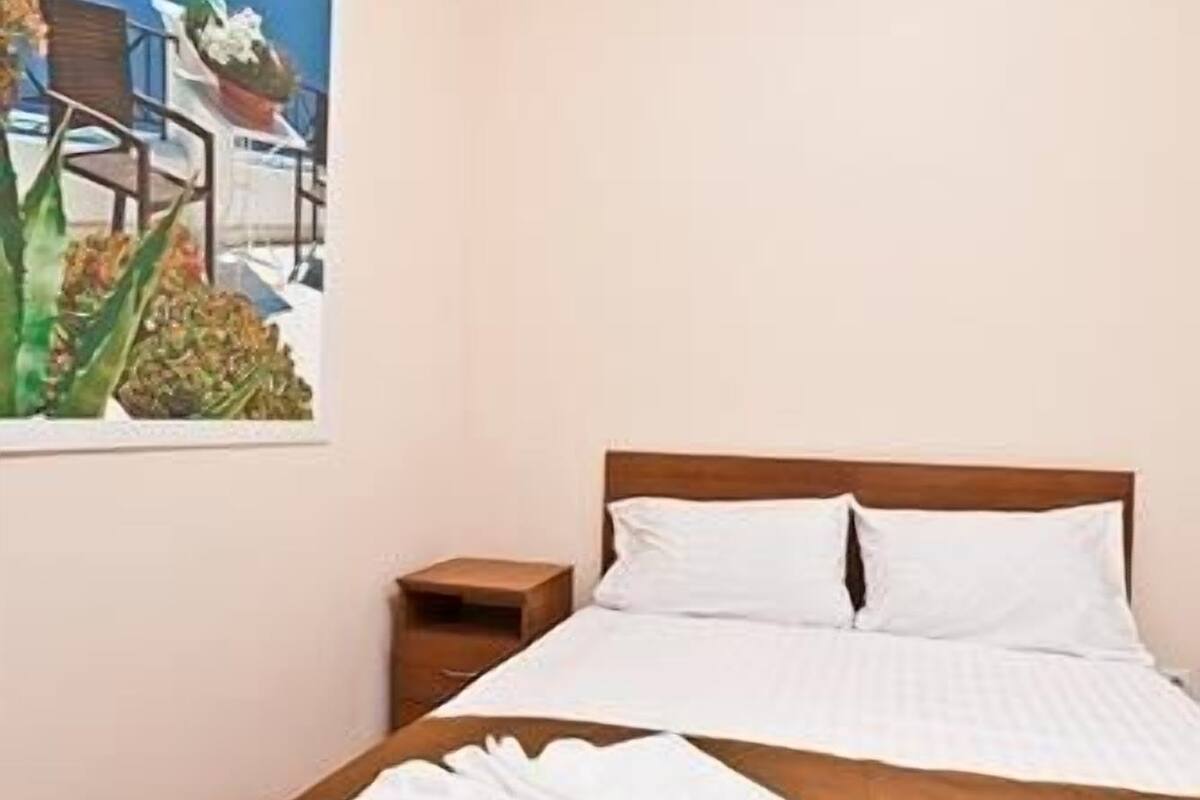A hotel room with a bed, a nightstand, and a painting on the wall.