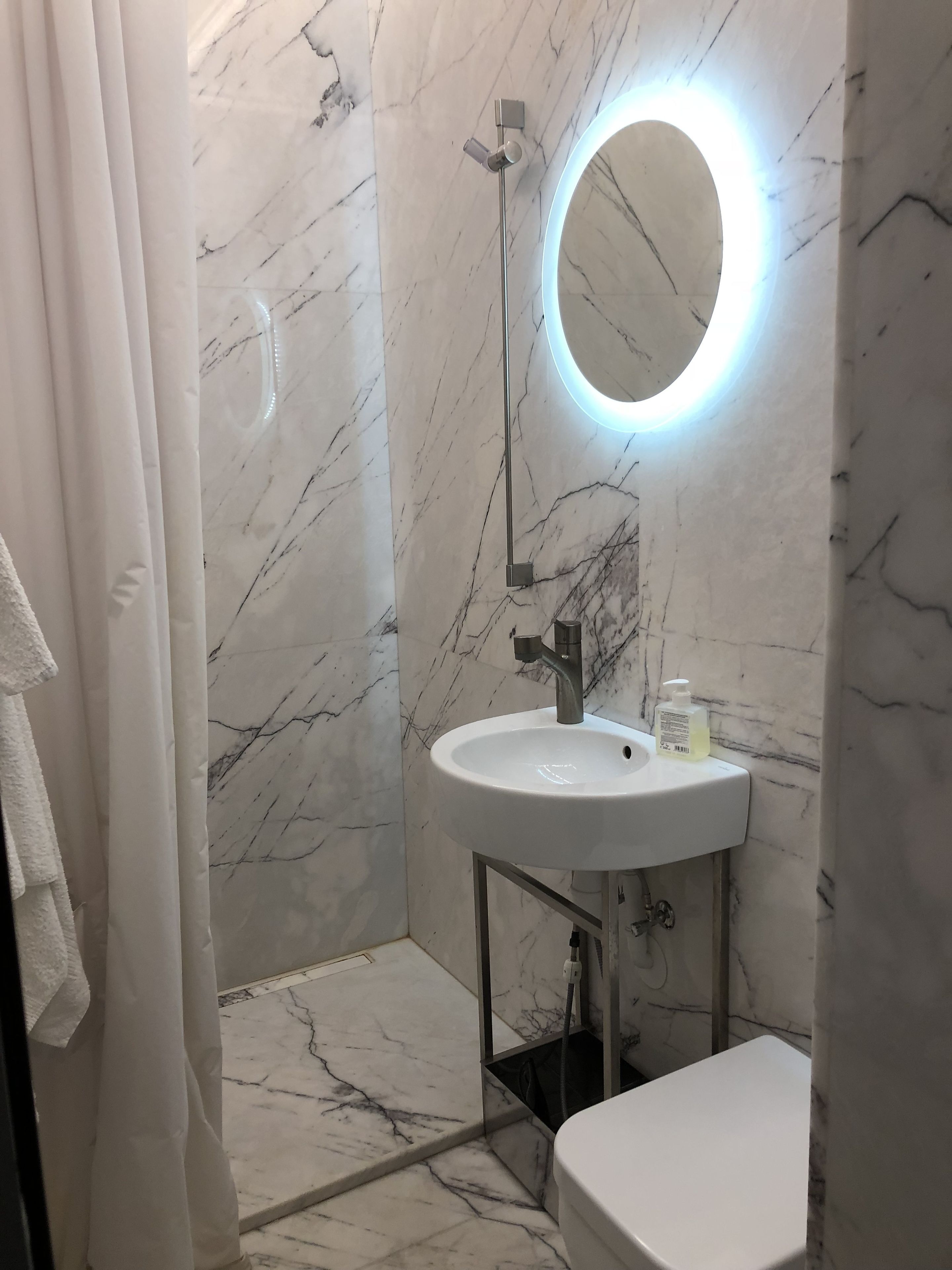 A bathroom with a marble floor, a white sink with a mirror above it, and a toilet.