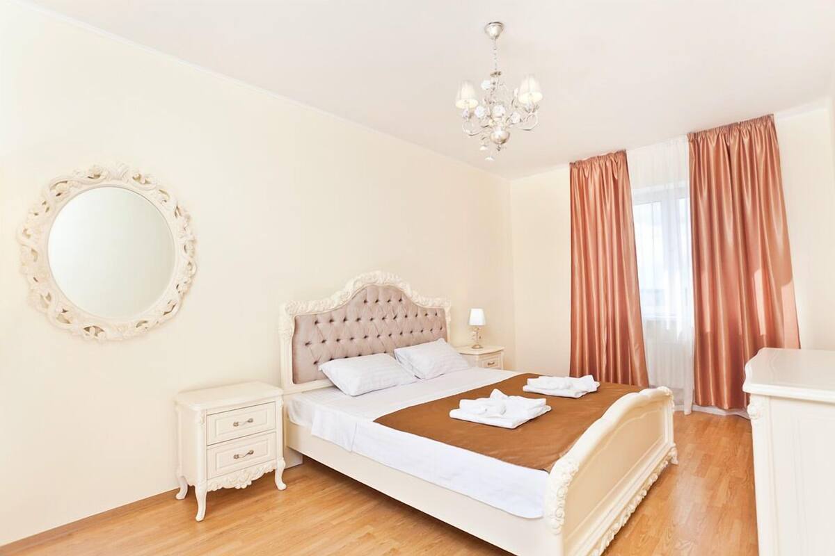 A bedroom with a bed, nightstand, dresser, and a mirror.