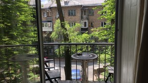 A balcony with a view of a brick building, a table, and chairs. - Lukyanovsky (Kyiv)