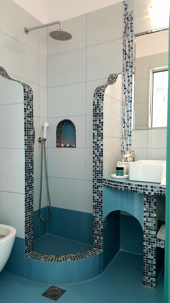Un baño con zona de ducha, lavabo y espejo.