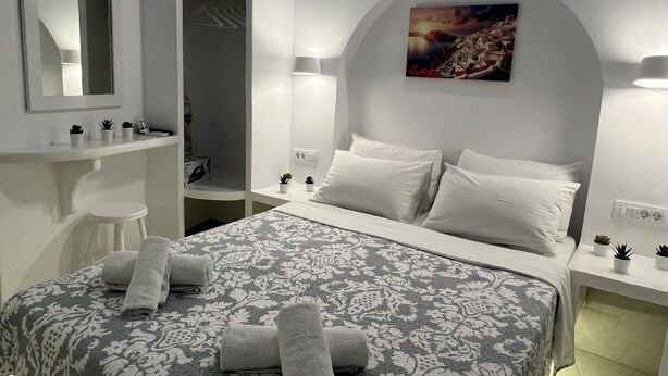 Una habitación de hotel moderna con una cama grande, un baño con espejo y un cuadro en la pared.