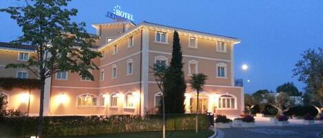 A multi-story hotel with a well-lit entrance and a sign indicating it is a hotel.