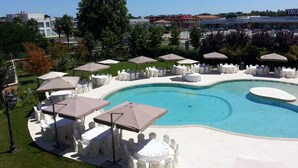 A swimming pool with white lounge chairs and umbrellas, surrounded by a landscaped garden. - Villa Michelangelo (Citta Sant'Angelo)