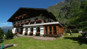 A traditional Alpine chalet with a sloped roof, wooden balconies with flower boxes, and a well-maintained lawn. - Landhaus Edelweiss (Sankt Leonhard im Pitztal)