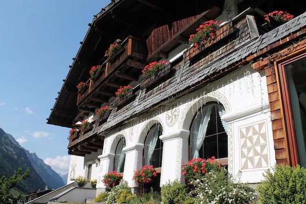 A traditional chalet with wooden balconies, arched windows, and flower boxes.