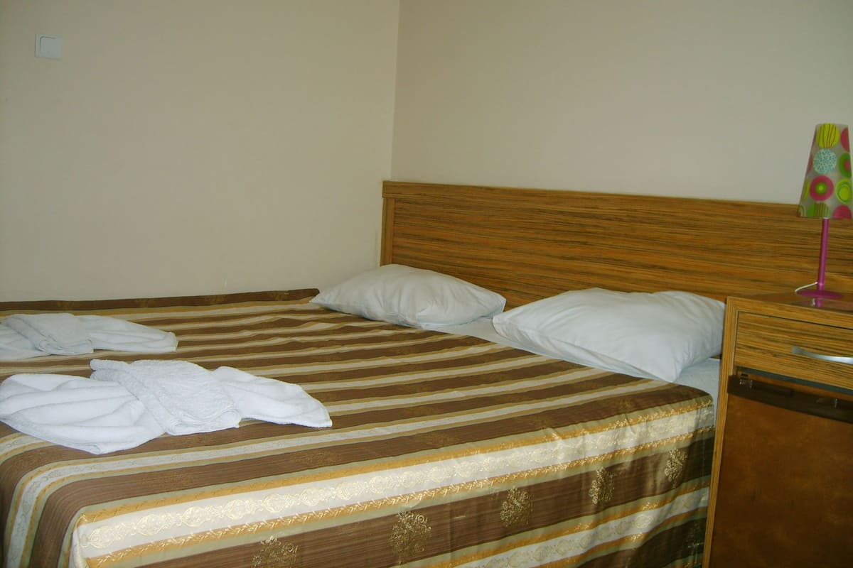 A single bed with striped bedding, two pillows, and a wooden headboard.