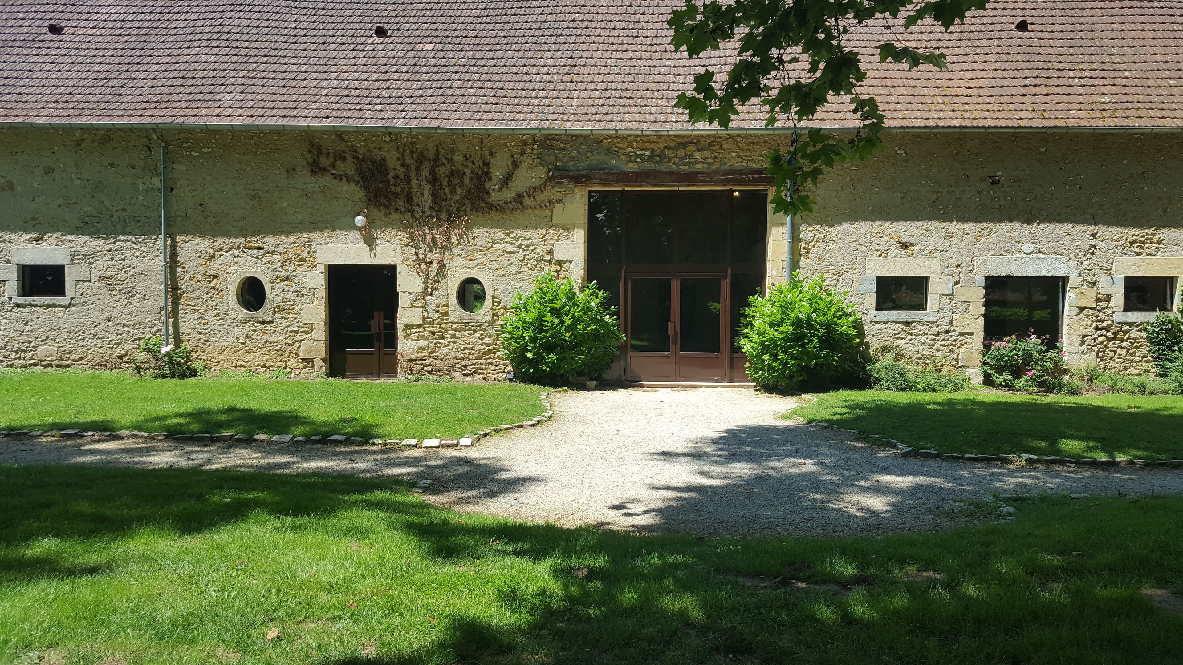 A stone building with a tiled roof, a central entrance, and small windows.