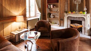 Una habitación tradicional con paneles de madera, chimenea, estanterías y sillones de cuero.