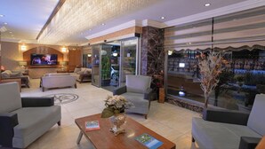 A spacious lobby with comfortable seating, a television, and a large window offering a view of the city. - Hotel Akyildiz (Istanbul)