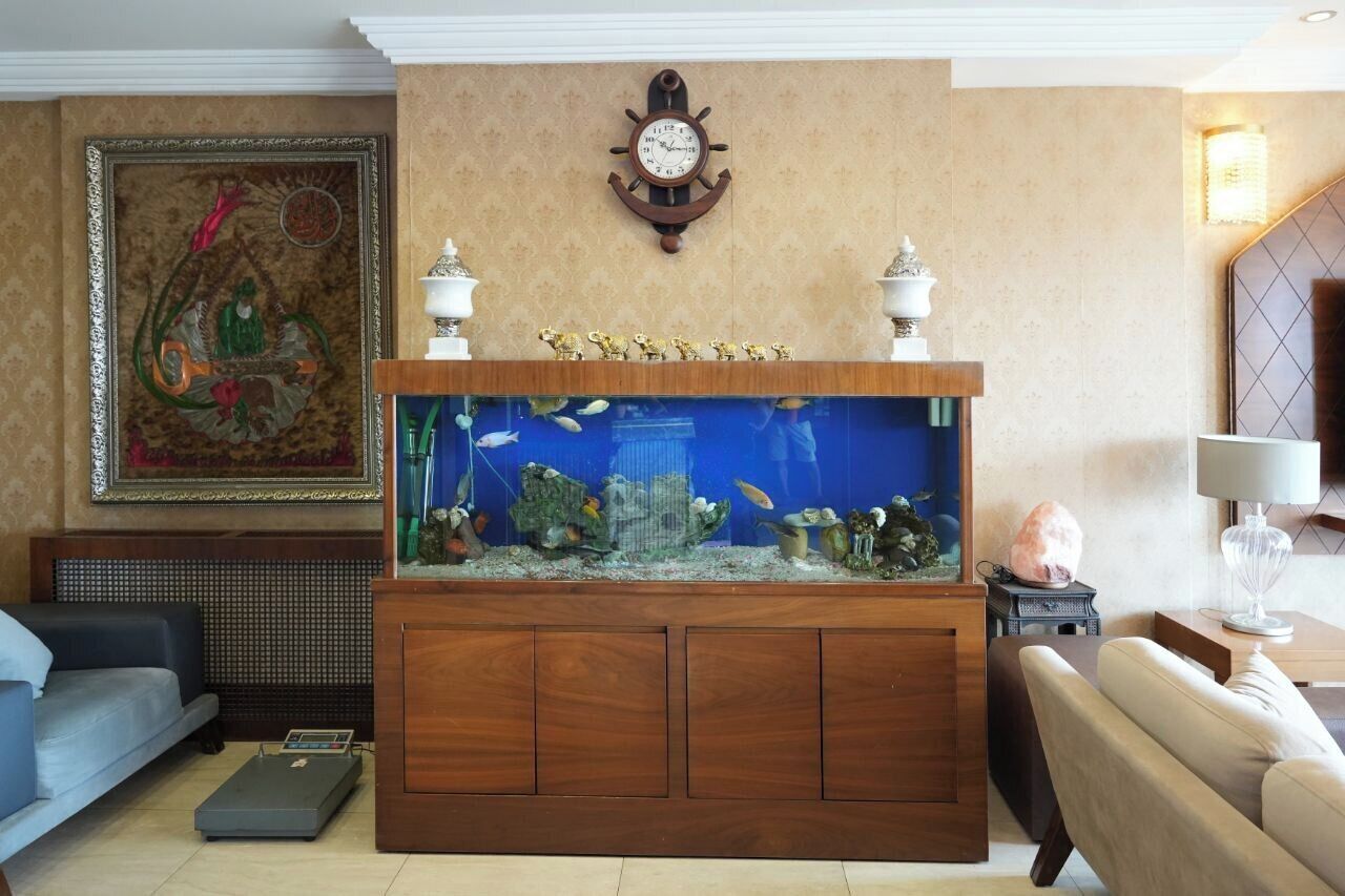 Un salon avec un grand aquarium, une horloge et un canapé.
