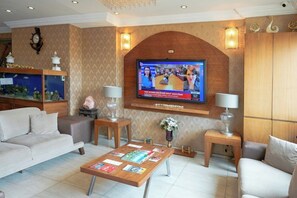 A modern living room with a television, sofas, a coffee table with magazines, a fish tank, and decorative wall sconces. - Hotel Akyildiz (Istanbul)