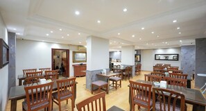 A spacious dining area with multiple wooden tables and chairs, a central island with a sink, and a kitchen in the background. - Hotel Akyildiz (Istanbul)