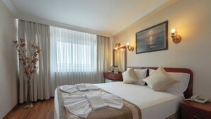 A hotel room with a large bed, a bedside table with a lamp, a mirror, and a painting on the wall. - Hotel Akyildiz (Istanbul)