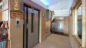 A hotel lobby with a check-out and check-in sign, an elevator, a staircase, and a mirror with a decorative frame. - Hotel Akyildiz (Istanbul)