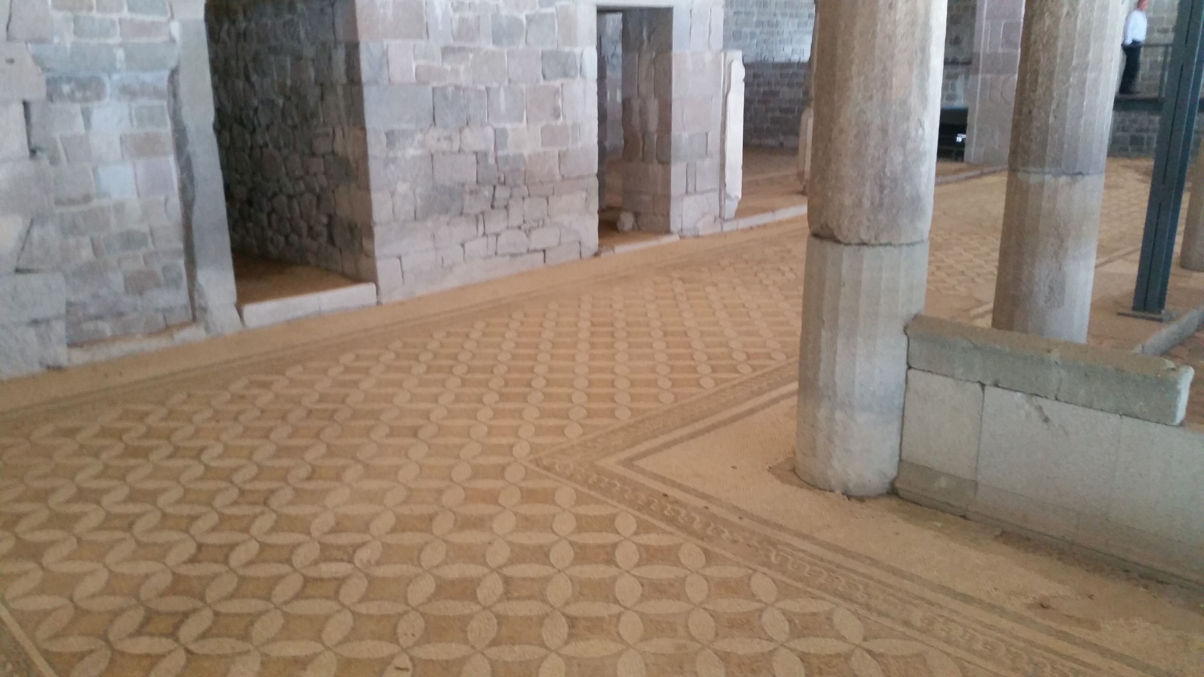 A room with a patterned floor, stone walls, and a doorway leading to another area.
